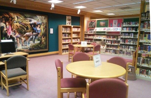 The Young Adult Room in Eureka Library with tables, chairs, and books.