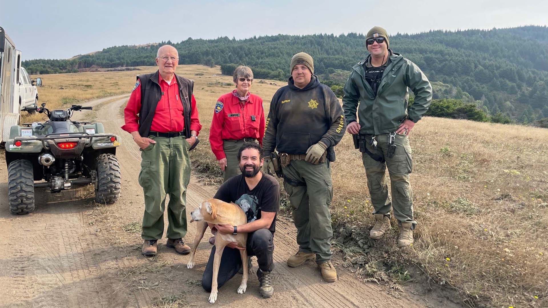 Rescued hiker and his dog take a photo with rescuers