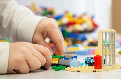 A child's hands work on a LEGO construction.