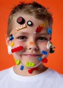 This kid is a LEGO monster! He has lego pieces stuck all over his face.