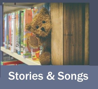 A fuzzy teddy bear peeks out from a bookcase to welcome you.