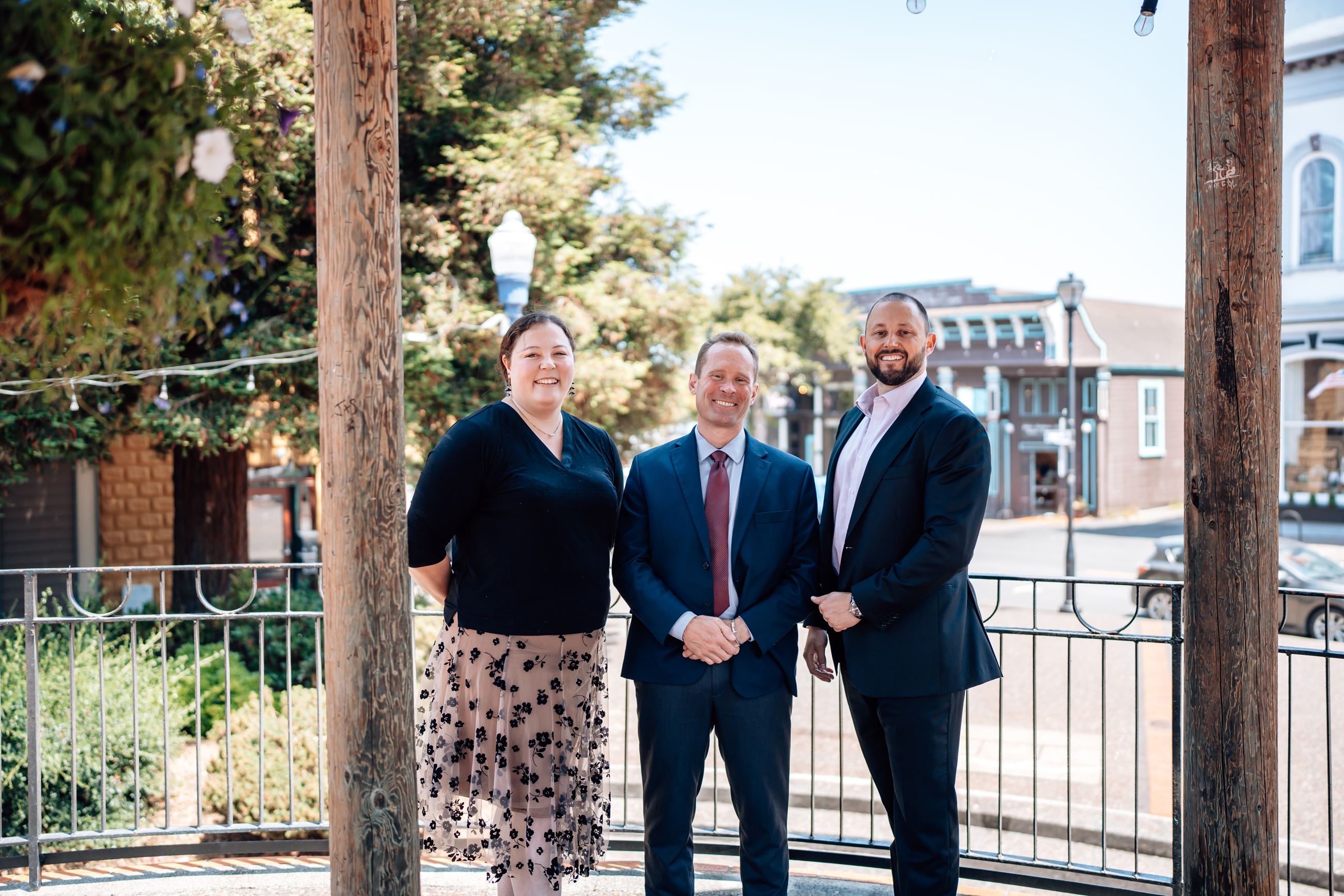 Three staff members from the District Attorney Office smiling at the camera, wearing professional attire.
